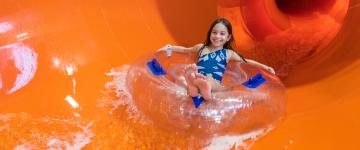 A little girl rides a tube down a slide at Kalahari's water park