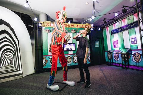Clown stands over a child at the Phobia2 Exhibit 