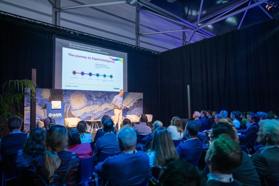 A man stands on stage and teaches adults at a trade show