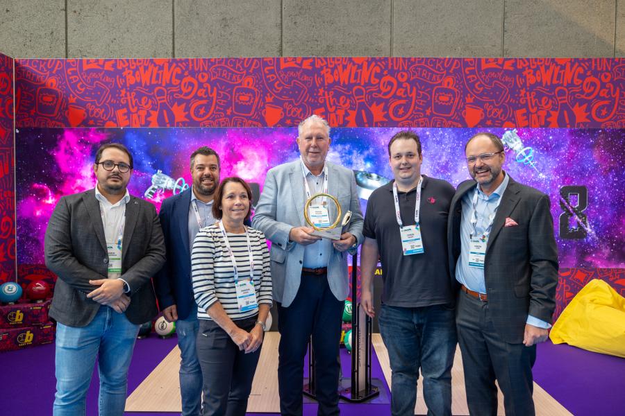 Employees of Bowl Easy stand in their booth grinning from ear to ear after winning a Brass Ring Award.