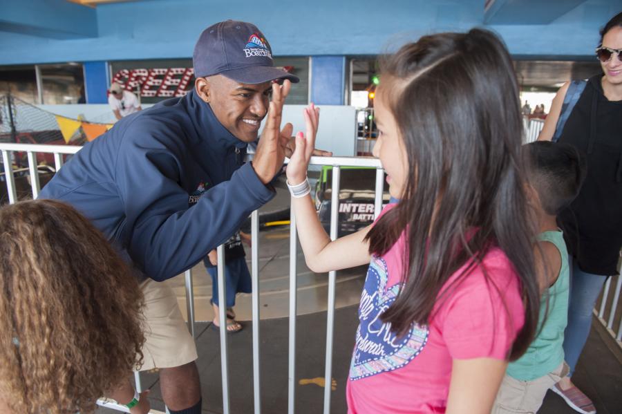 A Santa Cruz Beach Boardwalk employee high-fives a young guest waiting in line for bumper cars attraction
