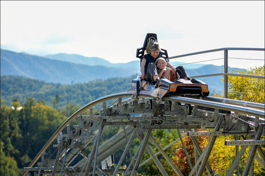 An adult and child ride the Hellbender Coaster inline seating