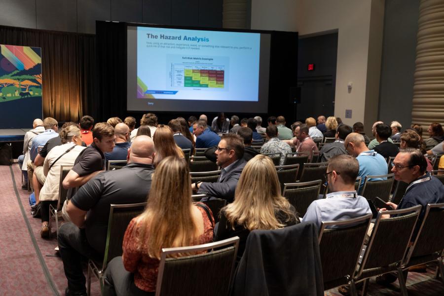 Attendees overlook a projector screen with a PowerPoint displaying "The Hazard Analysis" during a risk assessment EDUSession at IAAPA Expo 2023