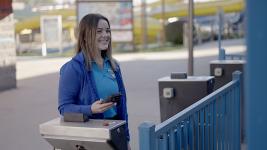 An amusement park employee smiling and holding a smartphone with a mobile scanner to scan ticket entry