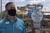 Chris Ozimek stands in front of Island H20 Live! sign with water slide in the background